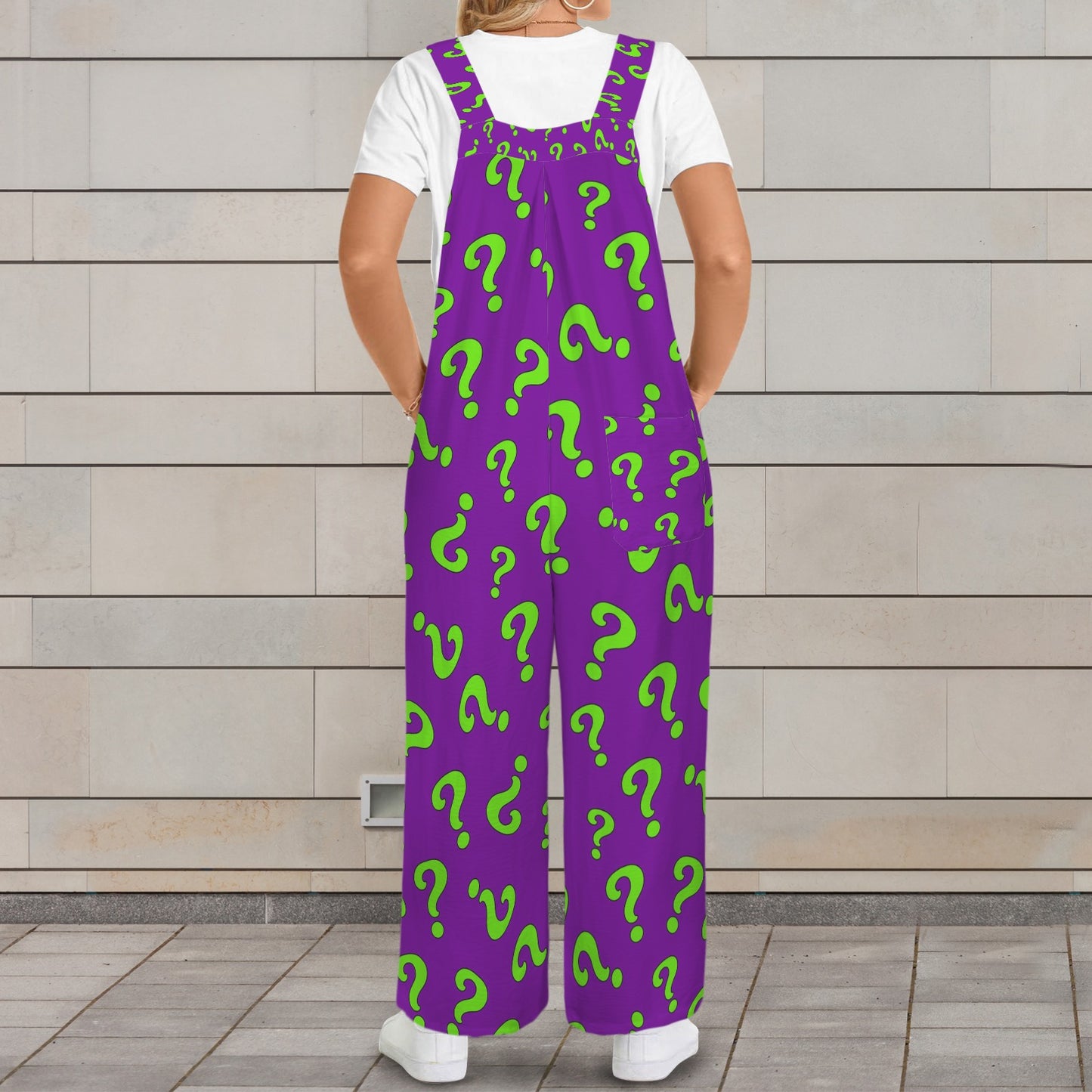 Person wearing purple overalls with green question mark pattern against a wooden wall.