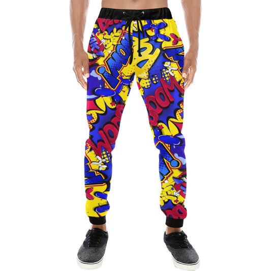 A pair of jogger-style pants with a vibrant multicolor graffiti pattern in blue, yellow, and red, featuring black cuffs and a black drawstring waist, modeled on a person against a white background.