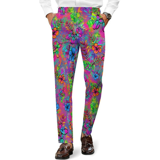 A person wearing slim-fit trousers with a vivid multicolor floral and tropical leaf print in pink, purple, blue, green, and orange, paired with a white shirt and brown loafers against a plain white background.