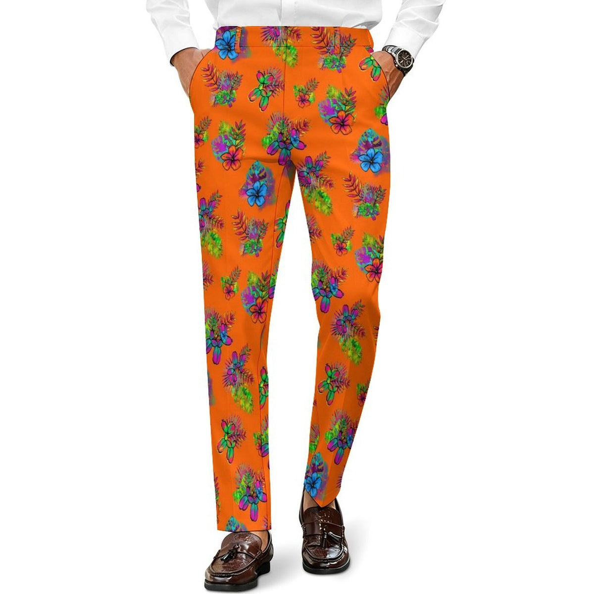 Bright orange slim-fit trousers with a colorful floral and leaf print with balloon dogs, worn by a model with a white shirt and brown loafers on a white background.